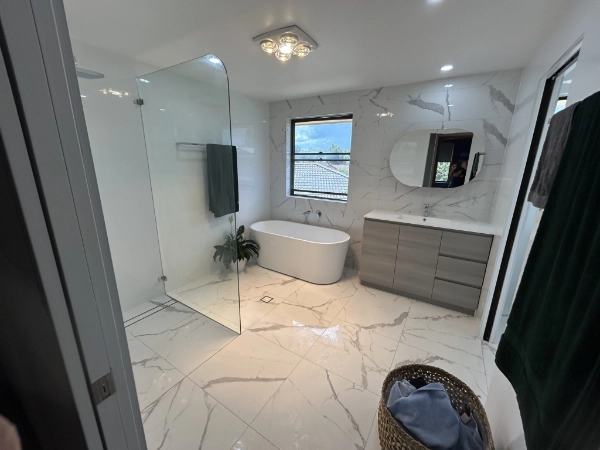 Completed bathroom renovation with a freestanding bath, glass shower and vanity