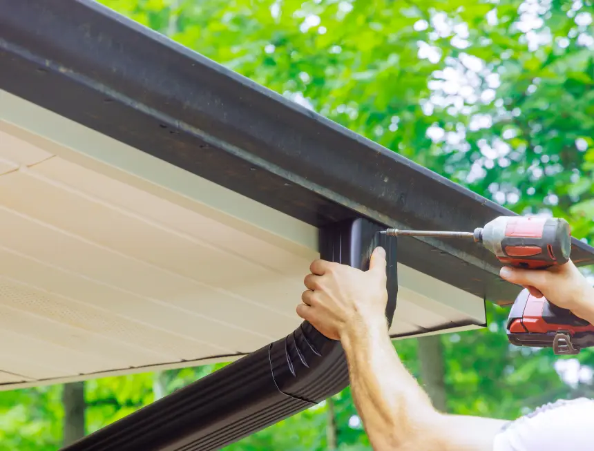 Tradesperson repairing and installing a metal gutter and downpipe