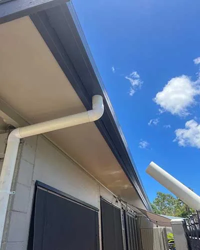 New gutter and downpipe against a bright blue sky