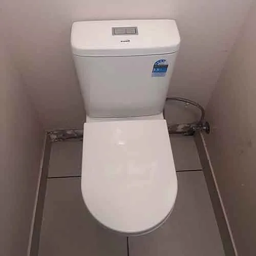 New white toilet installed in a compact bathroom