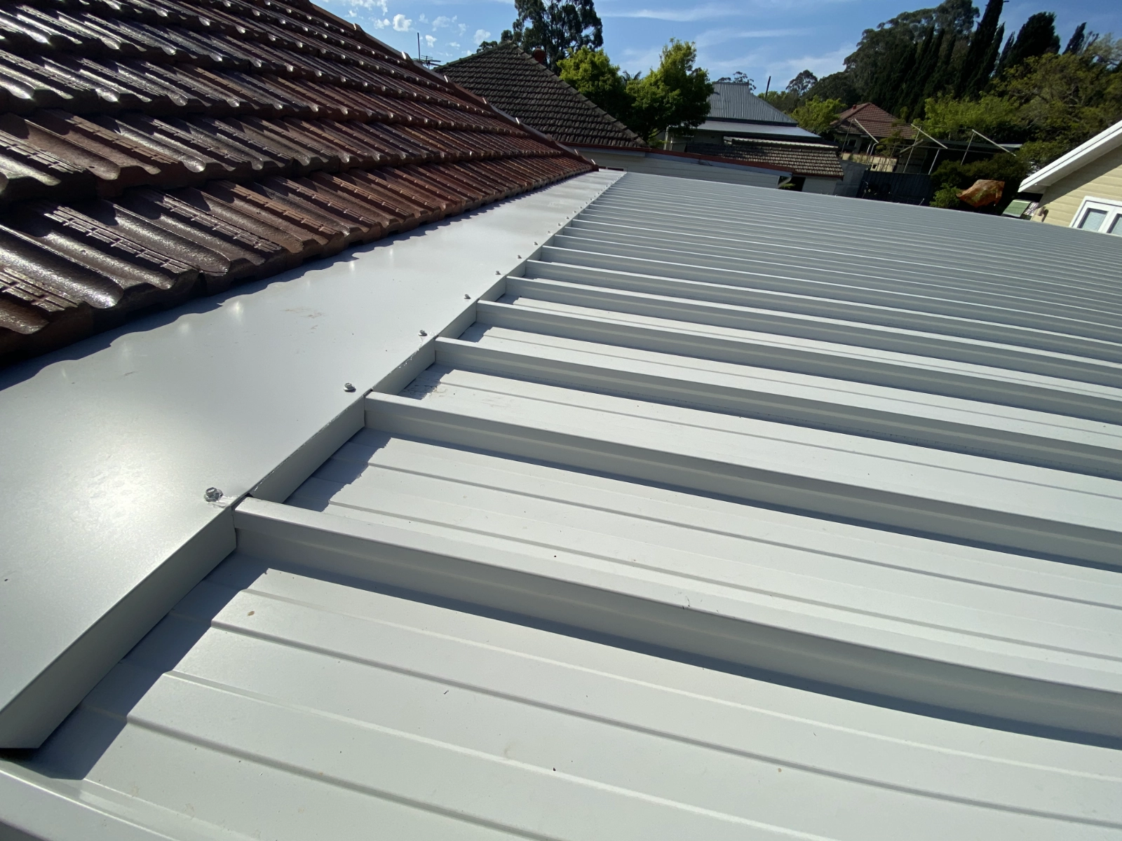 Formed metal flashing installed between tile and metal roofing